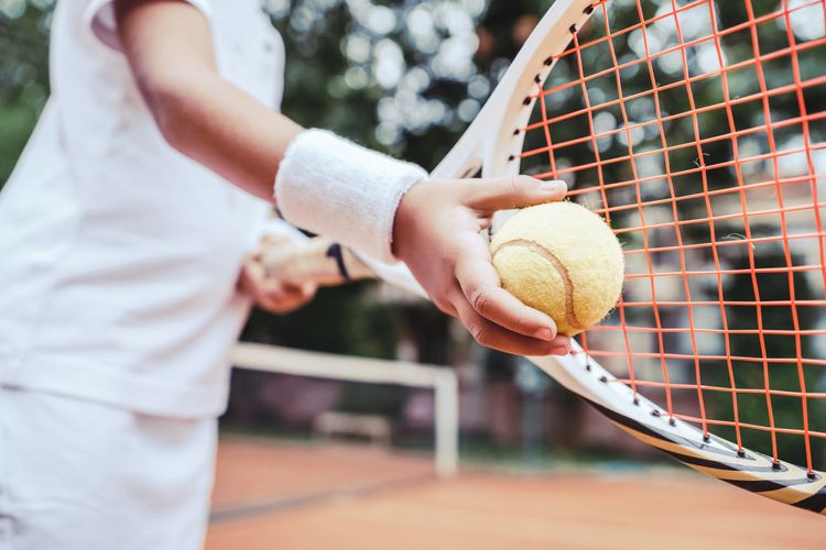 Dieťa s tenisovou raketou sa učí hrať tenis